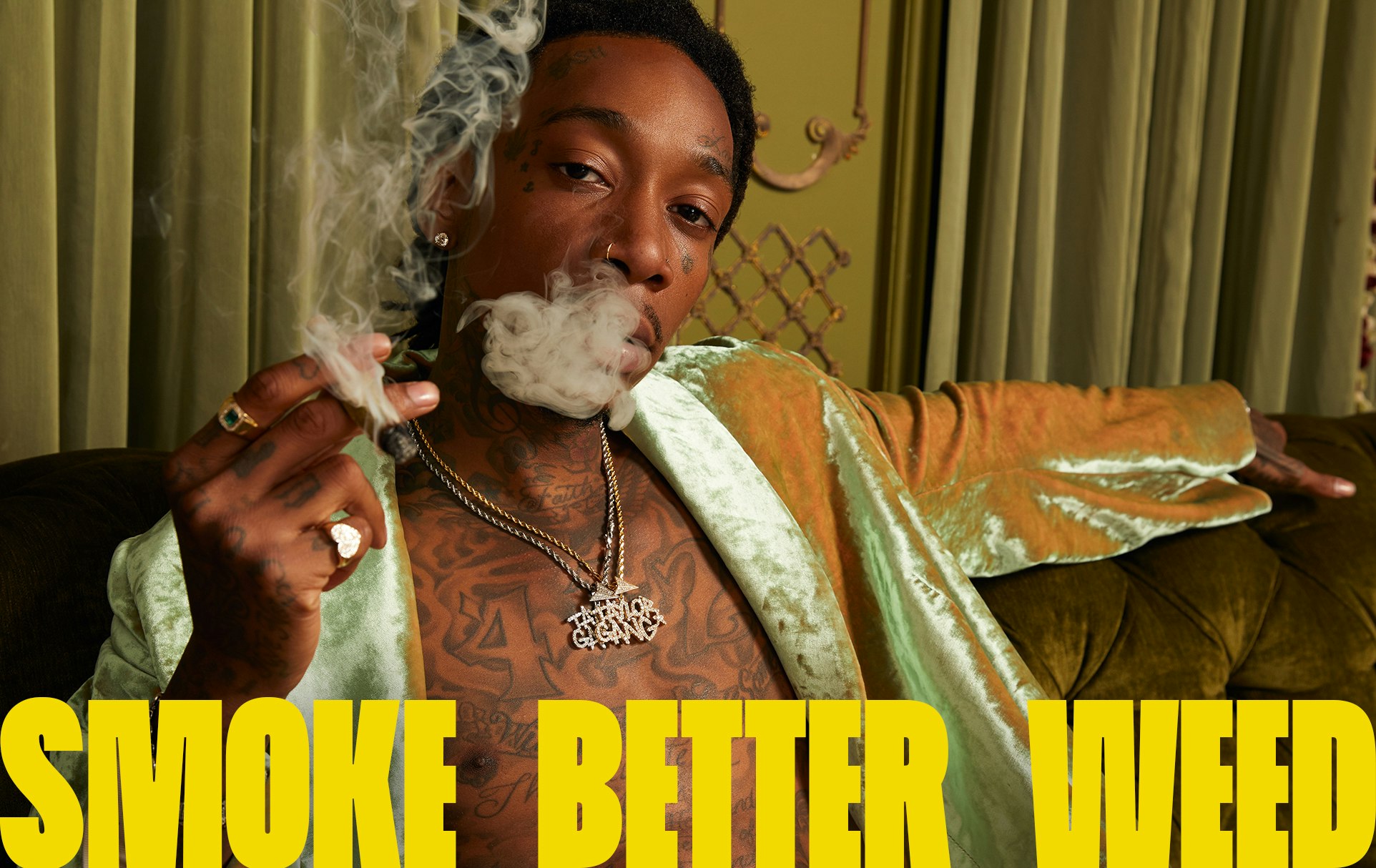 An image of Wiz Khalifa smoking sitting on a lounge chair with the words 'Smoke Better Weed'